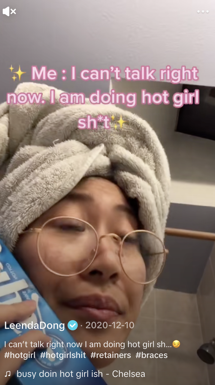 A woman in her bathroom pretends to talk on the phone, saying "I can't talk right now. I am doing hot girl sh*t."